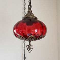 a red glass light hanging from a chain