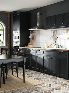 a kitchen with black cabinets and an arched doorway leading to the dining room area is shown