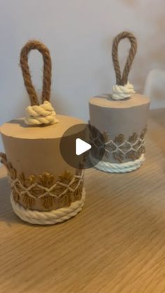 two small baskets with rope on them sitting on a table