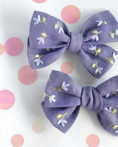 two purple bows with yellow and white flowers are on a polka dot tablecloth background