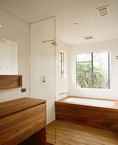 an empty bathroom with wooden flooring and large window overlooking the trees in the distance