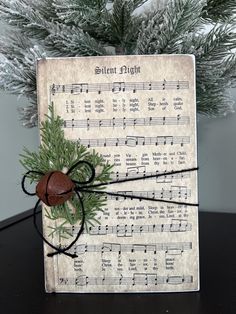 an old sheet with musical notes on it and a bell hanging from the top, next to a christmas tree