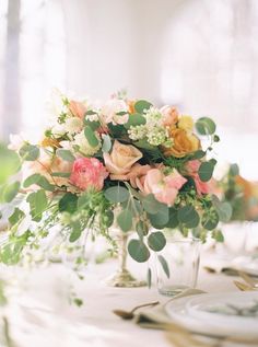 a vase filled with flowers sitting on top of a white tablecloth covered dining room table