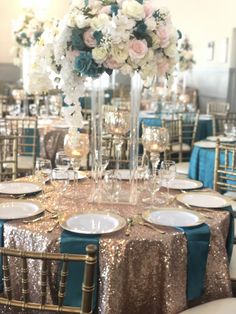 the table is set with gold sequins, blue and white flowers, and silver plates