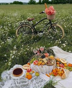 a bicycle is parked in the middle of a field filled with fruit and pastries