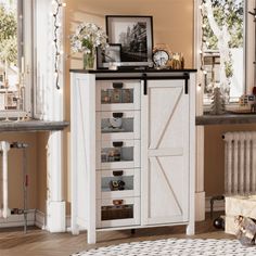 a white cabinet with lots of drawers in a living room next to a table and window