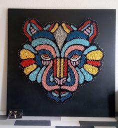 a colorful beaded bear head on a black and white checkered floor with a wall in the background