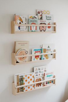 two wooden bookshelves with children's books on them against a white wall