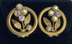 Auroura Borealis And Faux Pearl Floral Clip On Earrings  Wedding Earrings Sturdy clip. Gold Toned, some oxidation on the back.  Circle design with 3 Auroura Borealis stones, leaves and a single faux pearl.  Great for a vintage wedding. Gold Costume Jewelry Clip-on Earrings For Wedding, Gold Clip-on Costume Earrings For Wedding, Clip-on Costume Jewelry Earrings For Wedding, Vintage Clip-on Hoop Earrings For Party, Round Metal Flower Earrings For Weddings, Cute Purses, Earrings Wedding, Circle Design, Wedding Earrings