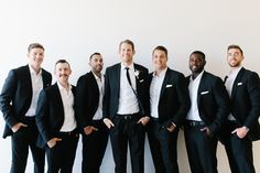 a group of men standing next to each other wearing suits and ties, all smiling at the camera