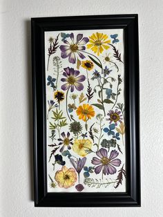 a painting hanging on the wall next to a framed flower art piece in a black frame