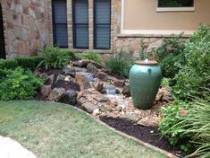 a large green vase sitting in the middle of a garden next to a stone building