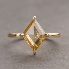 a yellow diamond ring on a gray surface with the top half cut off and one side missing