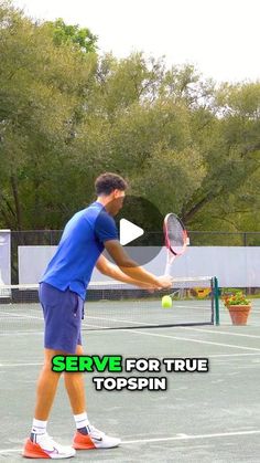 a man holding a tennis racquet on top of a tennis court with trees in the background