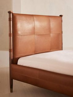 a brown leather bed frame with white sheets