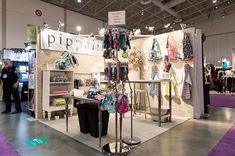 a booth at a trade show with clothing on display and people looking at items in the background