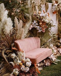 a pink couch surrounded by flowers and plants