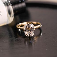 an engagement ring sitting on top of a table next to a bottle