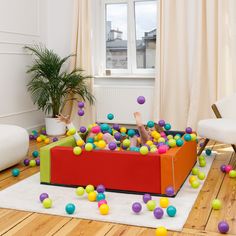 a person laying in a ball pit with balls all over the floor and on the ground