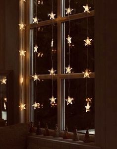 the window is decorated with white stars and lights hanging from it's windowsill