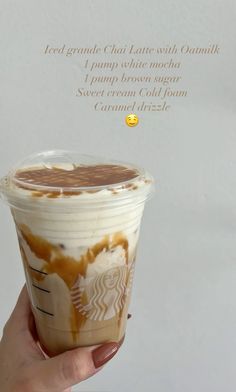 a hand holding up a cup of coffee with whipped cream and caramel drizzle