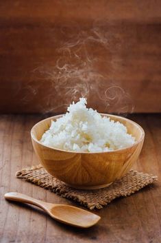 a wooden bowl filled with rice on top of a table