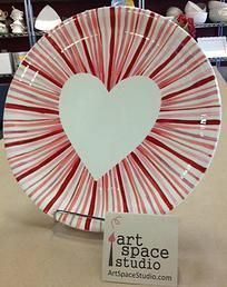 a heart shaped plate with red and white stripes on the rim, sitting on a table