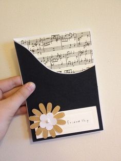 a hand holding up a piece of paper with music notes on it and a flower