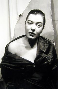 a black and white photo of a woman in a leather dress with her mouth open