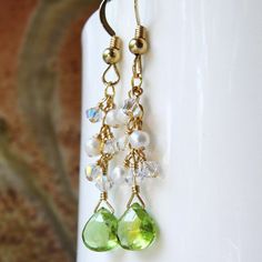 Peridot stone and pearl dangle earrings are handmade with beautiful petite peridot gemstones with gorgeous clarity and color. White freshwater pearls and sparkly and bright white Swarovski crystals cascade down a 14k gold filled chain. A gorgeous dangle pair of earrings which is a little flirty but can still be worn to work and to play afterwards. Give a thoughtful birthday gift to a woman born in August since peridot is her birthstone. Earring Details: - Peridot gemstones are 6 mm tall and 6 mm Briolette Dangling Beads Earrings Gift, Gift Briolette Earrings With Dangling Beads, Wire Wrapped Dangle Earrings For May Birthstone, Elegant Wire Wrapped Earrings For May Birthstone, May Birthstone Pearl Drop Dangle Jewelry, Pearl Earrings Gold, Bridal Party Jewelry, Peridot Jewelry, Peridot Earrings