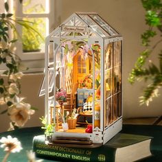 a doll house sitting on top of a green table next to a potted plant