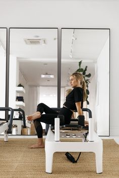 a woman sitting on top of a white table in front of a mirror with her legs crossed