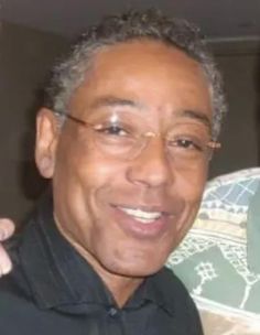 an older man wearing glasses and a black shirt smiling at the camera with his hand on his shoulder