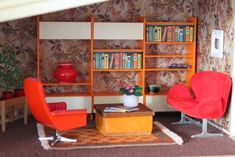 a living room filled with furniture and bookshelves next to a wallpapered wall