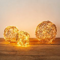 three lighted balls sitting on top of a wooden floor