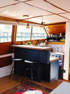 a kitchen with two stools next to an island in the middle of a room