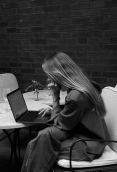 a woman sitting at a table with a laptop computer