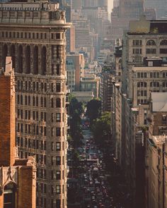 a city street filled with lots of traffic next to tall buildings in the middle of the day