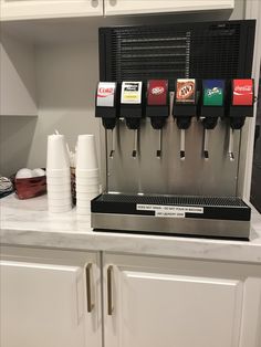 a coffee machine sitting on top of a counter next to white cupboards and cups