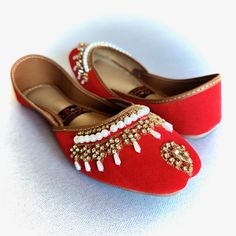 a pair of red shoes with beading on them