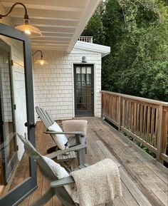 a wooden deck with two rocking chairs and a door leading to the back porch area