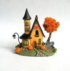 a small house with a tree and pumpkins on the ground in front of it