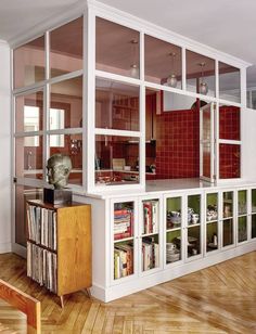 a living room filled with lots of furniture and bookshelves next to a red couch