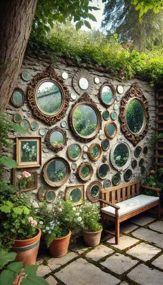 a stone wall with many mirrors on it and potted plants in the foreground