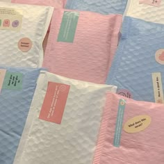 several pink and blue envelopes with stickers on them are lined up in rows