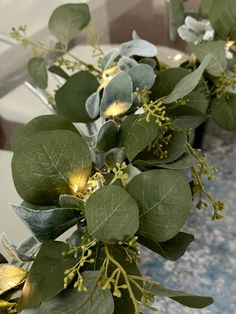 the table is set with green and white flowers, leaves and candles on it's side