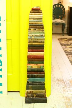 a stack of books sitting on the floor next to a yellow door in a room