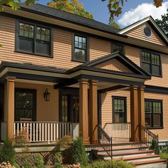 a large brown house with black trim on the front porch and stairs leading up to it