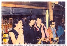 a group of young men standing next to each other in front of a shelf filled with bottles