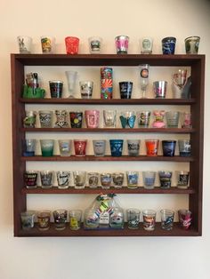 a shelf filled with lots of glasses on top of a wall next to a white wall